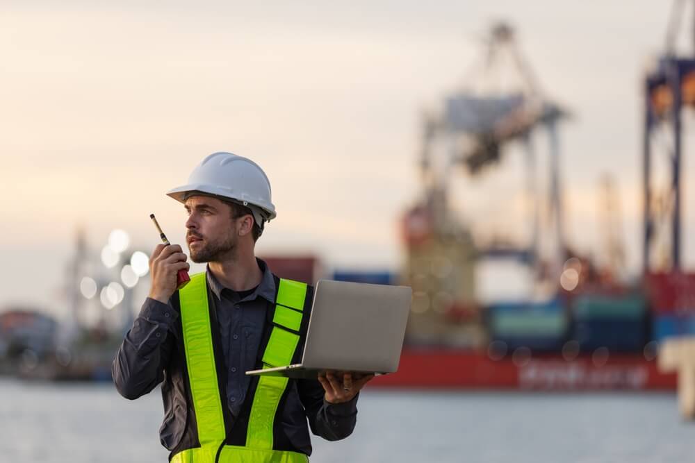 Das Bild zeigt einen Ingenieur mit Funkgerät und Laptop am Rostocker Hafen.